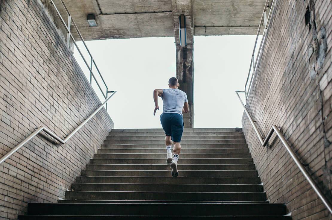 Young male athlete running up the stairs